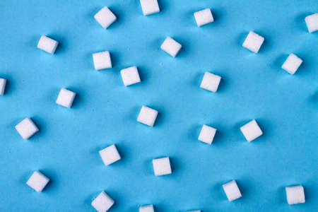 Sugar cubes on blue background. Granulated sugar is unhealthy food.の写真素材