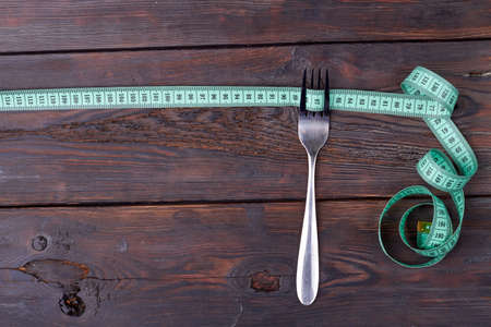 Measure tape with fork on wooden background.の写真素材