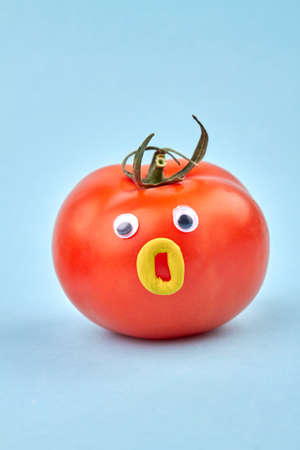 Funny humalike tomato with opened mouth. Isolated on blue background.の写真素材