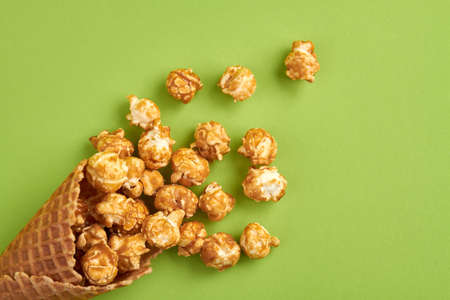 Sweet popcorn in an ice cream wafer. Top view sprinkled corns on green surface.の写真素材