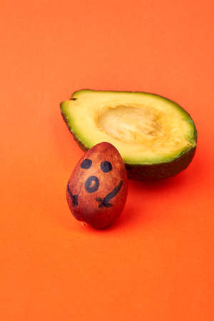 The seed who left an avocado. Avocado with separated seed isolated on orange background.