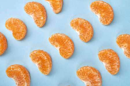 Rows of mandarin slices. Mandarin parts arranged in rows isolated on blue background.の写真素材
