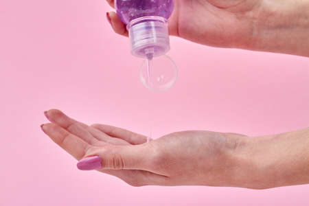 Womans squeezing shampoo on her palm. Close up transparent liquid soap flow from a bottle. Isolated...