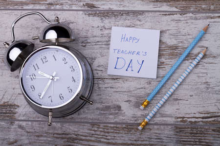 Composition of school items for happy teachers day. Still life of alarm clock and pencils on wooden...