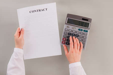 Female hands, business contract and calculator. Business woman using calculator while reading...