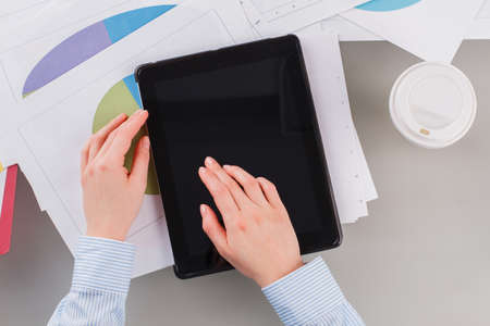 Workspace with female hands, digital tablet, documents and coffee cup. Flat lay office desk. Top...