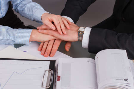 Close up stack of hands of business partners. Businessman and businesswoman showing unity putting...