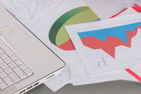 Close up of financial papers and laptop. Laptop and graphs on the desk. Business, finance and...