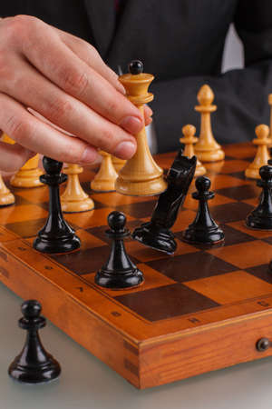 Male hands playing chess close up. Businessman playing chess moving the queen piece. Business tactic...