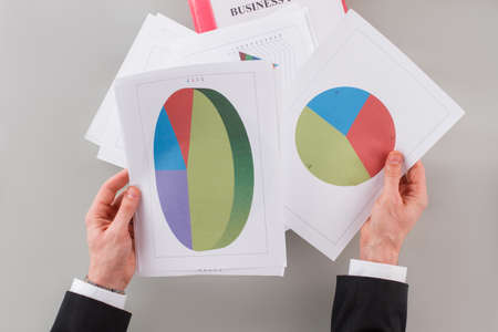 Businessman in suit analysing graphs and charts. Top view of male clerk working with documents.