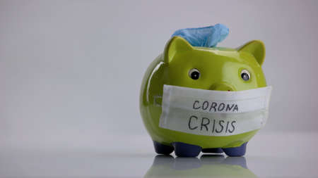 Green piggy bank with protective gloves. Savings for coronavirus pandemic.の写真素材