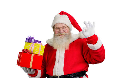 Portrait of Santa with gift boxes. Photo of realistic Santa Claus showing okey sign standing on...