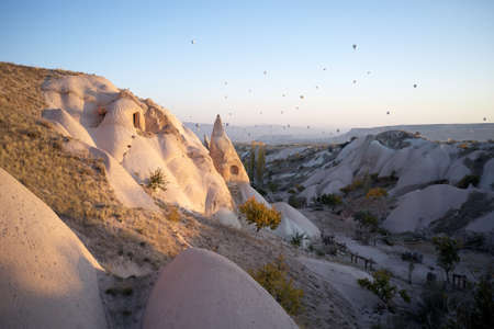 Beautiful view of morning Cappadocia valley. Hot air balloons flying over mountains. Rock formations in white valley. Must visit place of Turkey.の写真素材