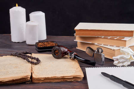 Still life composition books with pipe and candles. Vintage writers stuff on wooden table.