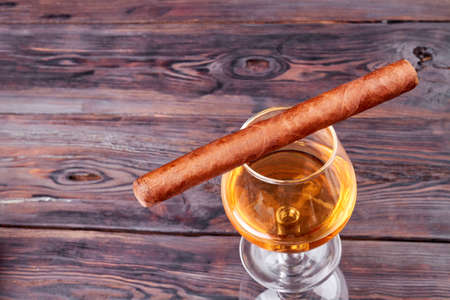 Cuba cigar and glass of brandy top view. Old rustic wooden background.の写真素材