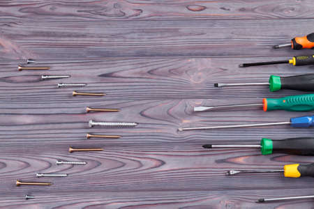 Row of screwdrivers on wooden desk. Grey wood and copy space.