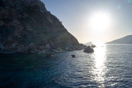 Cliffs on the tropical island coast. Sun shining over clear water of rocky coastline. Vacation on tropical island.の写真素材