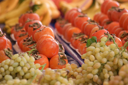 Fresh ripe fruits on market counter. Ripe green grape and persimmons on market stall. Healthy organic food.の写真素材