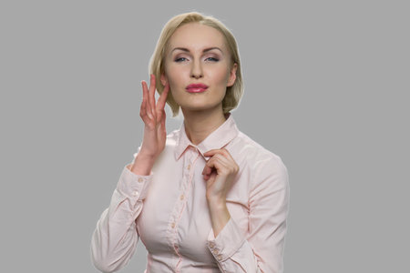 Sexy business woman touching her face. Beautiful seductive blonde woman touching her face with flirty expression.の写真素材