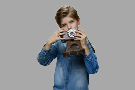 Little boy using vintage camera. Preteen boy in denim jacket taking picture with old retro camera.の写真素材