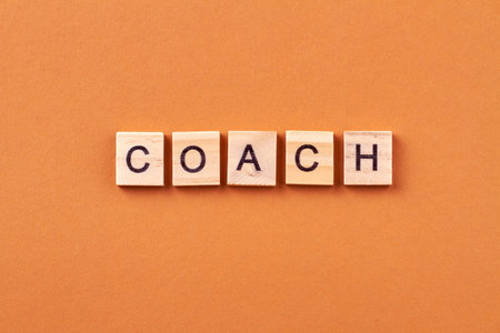 Coach is a specialist who is engaged in mentoring. Inspiration and motivation for business. Letters on wooden cubes isolated on orange background.の写真素材