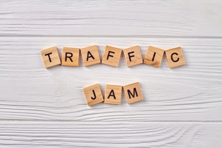 Traffic jam concept. Line of road traffic. Alphabet cubes with letters isolated on light wooden...