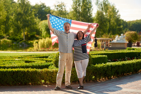 Happy aged couple holding flag of the united states. Patriotic senior man and woman.の写真素材
