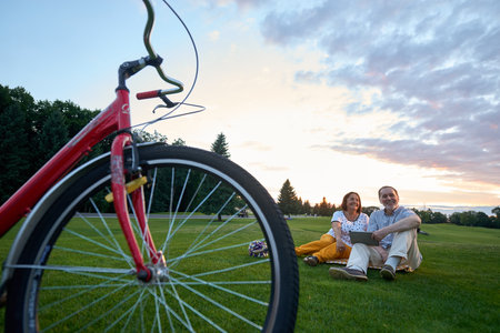 Red bike and happy couple on the grass. Bicycle on the grass.の写真素材