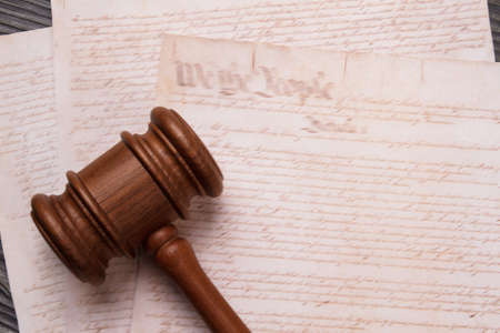 Close-up wooden gavel and old text. Papers with elder text and court judge hammer.