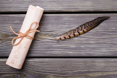 Old scroll and quill. Rolled paper with bow tie. Grey desk background.の写真素材