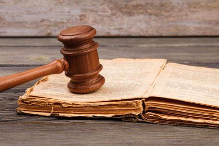 Old law book concept. Opened worn book with wooden court gavel.