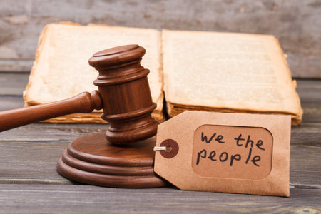 Trial and justice concept. Wooden gavel with law book and we the people slogan.の写真素材