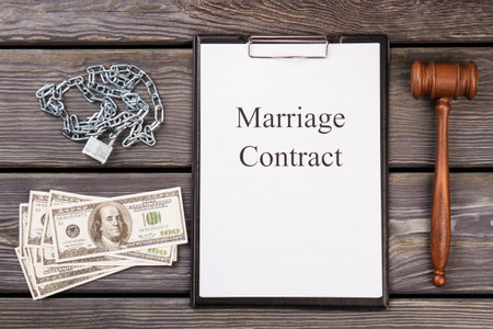 Marriage contract as a prison concept. Judge gavel with dollars and chain with padlok on wooden desk.の写真素材