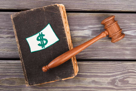 Old law book with dollar sign. Brown wooden judge gavel.の写真素材