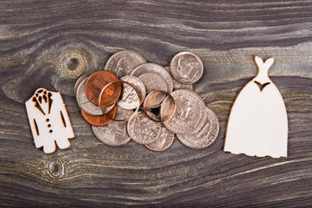 Top view pile of coins and two wedding rings. Wooden desk background.の写真素材
