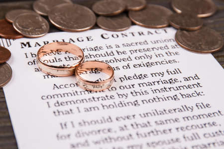 Marriage contract and wedding rings. Pile of coins.の写真素材