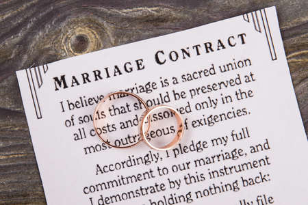 Marriage contract and wedding rings. Close-up paper with text and two rings close-up.の写真素材