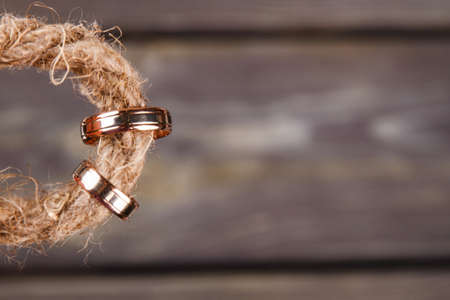 Wedding rings on the thread close-up. Dark wooden background.の写真素材