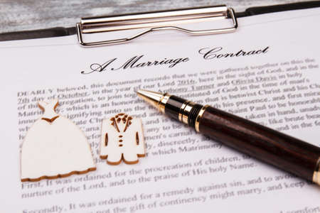 Marriage contarct and pen close-up. Clipboard and wedding dresses.の写真素材