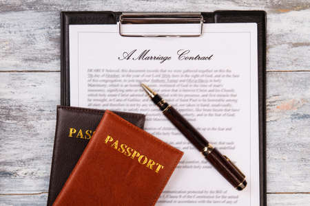Love and marriage concept. Marriage contract passports and pen on wood.
