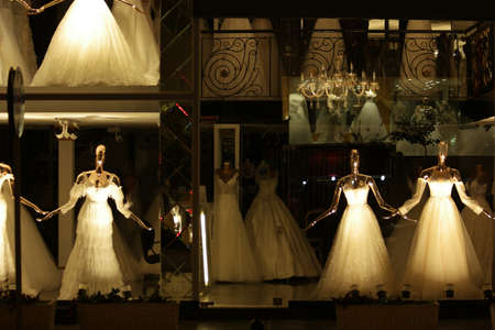 Bridal window display. Beautiful white wedding dresses on display. Fashion store with bridal dresses.の写真素材