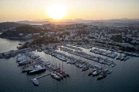 Aerial view of coastline and harbor in Bodrum, Turkey. Landscape with boats in marina bay. Picturesque sunset over mountains in the background.の写真素材
