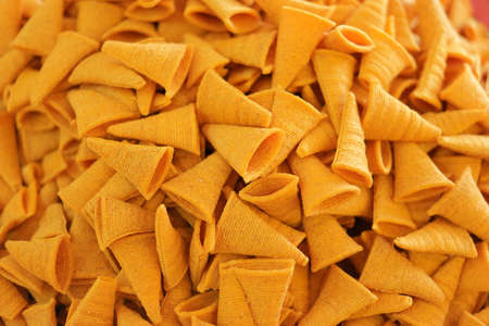 Triangle crunchy corn cheese flavor snack background. Background of crispy spicy corn snack.の写真素材