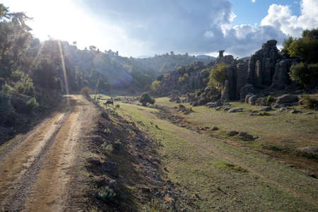 Countryside valley with rock formations in sunlight.