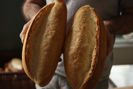 Hands of chef baker holding two loaves of fresh baked bread.の写真素材