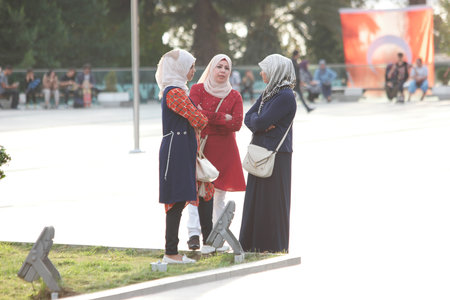 Three Muslim women in traditional hijab headscarf talking outdoors.のeditorial素材