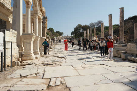 Tourists walking on an ancient paved street of Ephesus, Turkey.