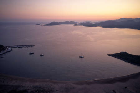 Landscape panorama with sea, boats and mountains at sunset.