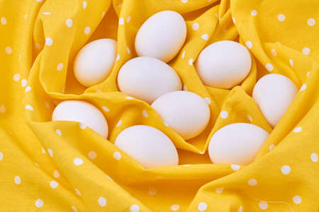Pile of white eggs on yellow fabric textile cloth.の写真素材