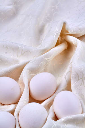 White organic chickens eggs on a beige textile cloth.の写真素材